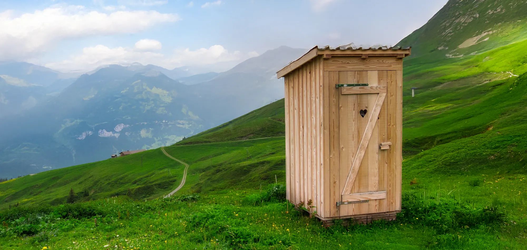 Holzklohäuschen auf einer grünen Wiese in den Bergen - Thema Verdauung