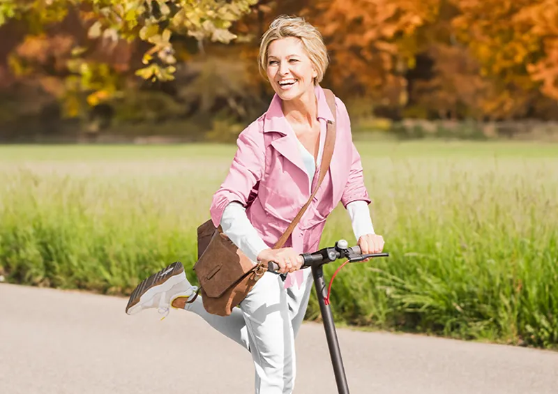 Frau fährt energetisch und glücklich Tretroller- Thema B-Vitamine 